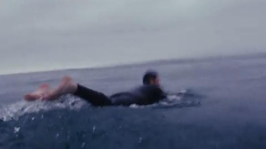 Surfer man diving waves with his surfboard in the middle of the sea