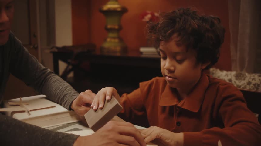 Father and son build a model airplane together at the dining room table