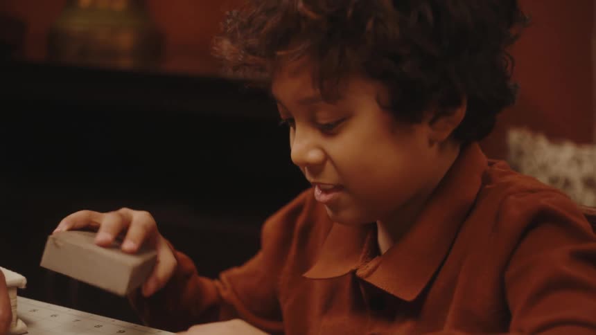 A boy sands a piece of wood while his father talks to him