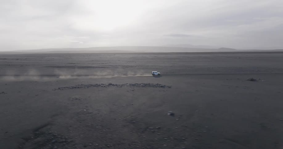 White vehicle traveling on desert soil one morning