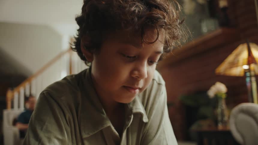 Boy writing while in the living room at home