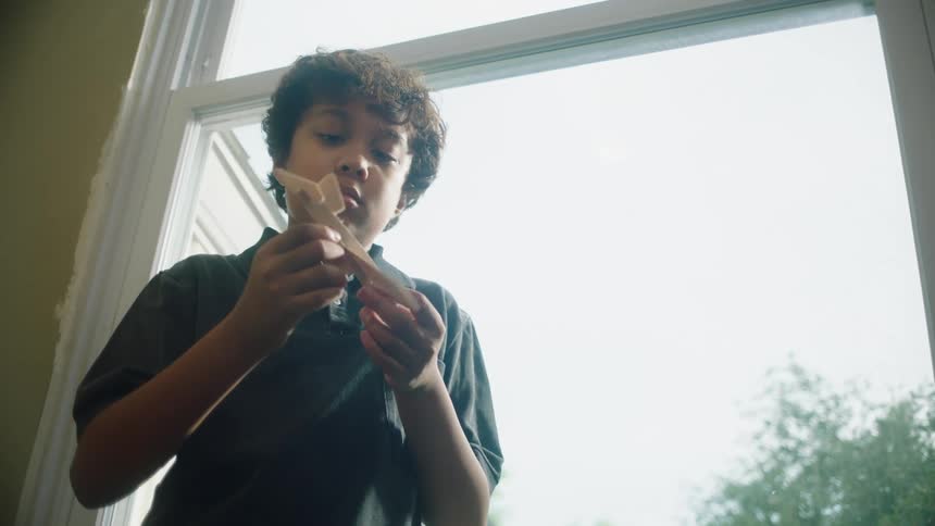 Boy indoors holding a cardboard plane