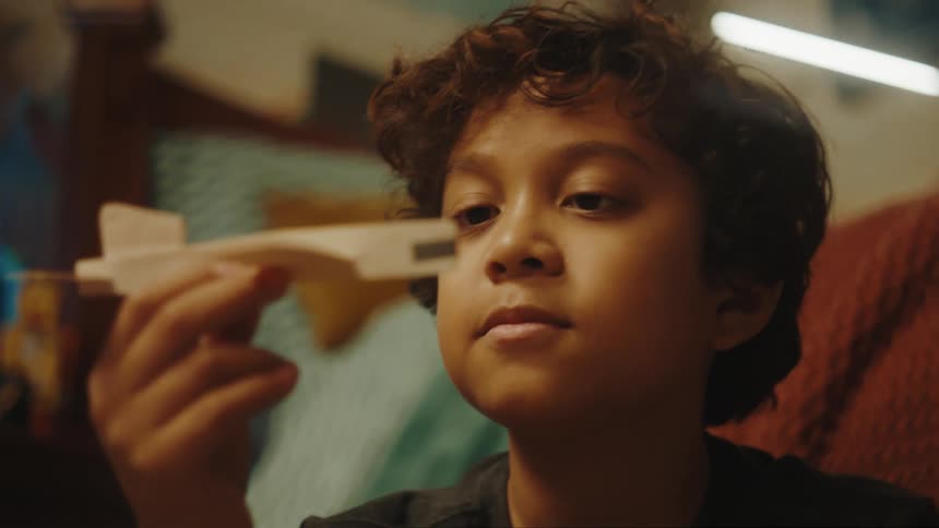 A young boy gazes at a toy plane