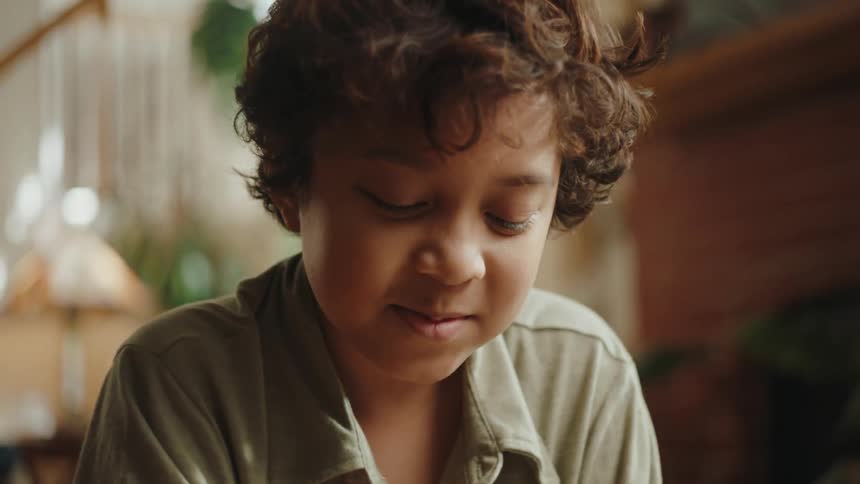 A little boy smiles at something while his dad reads in the background