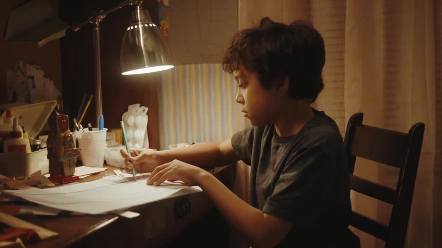 A boy doing homework on a desk in the bedroom