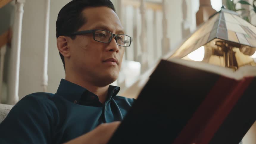 A man reading a book in a cozy room at home