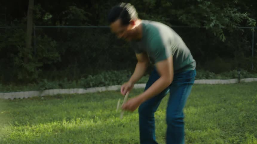Man catching a cardboard plane that lands on the lawn and throwing it into the air while outdoors