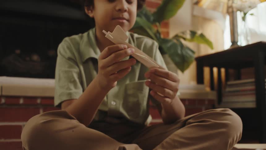 A boy making toy paper planes in the living room