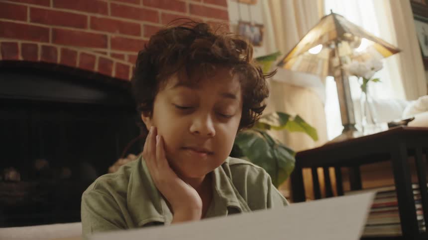 Portrait of a boy sitting and looking at a drawing on a sheet of paper