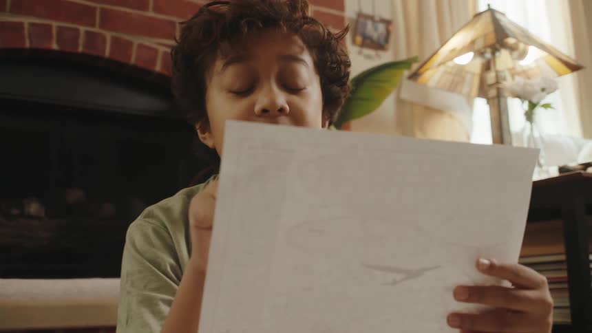 Boy sitting in the room and reading a project on a white paper