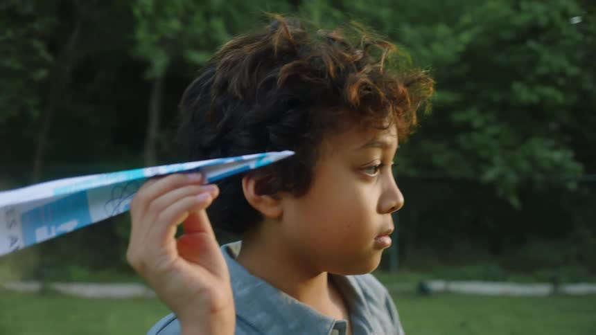 Portrait of a little boy with a paper airplane playing in an openair environment