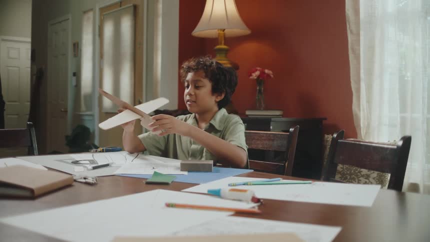 A boy making toy paper planes in the living room
