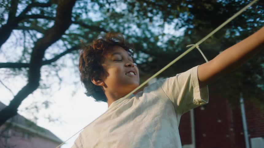Boy in the backyard playing toss a toy plane with a rubber band