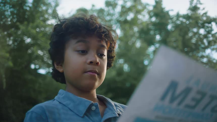 A young boy nods his head while reading a sign