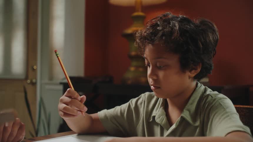 Boy sitting drawing at the table next to his father