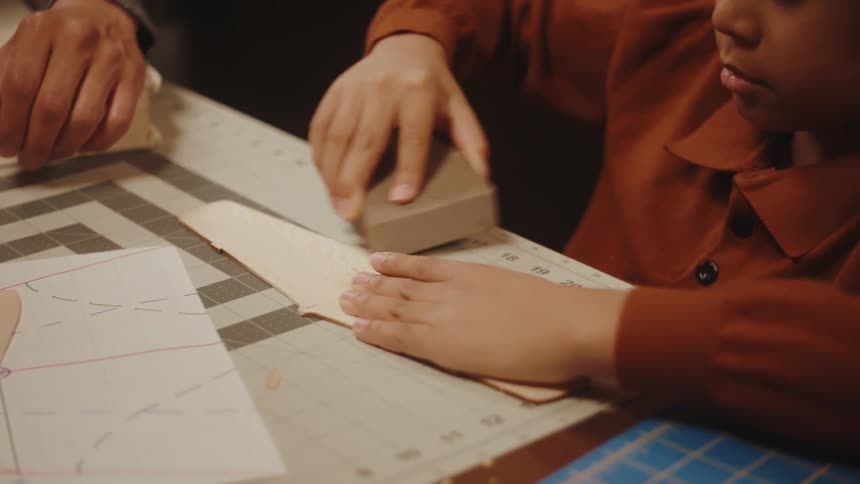 A boy sanding down and smoothing a piece of wood from a model toy