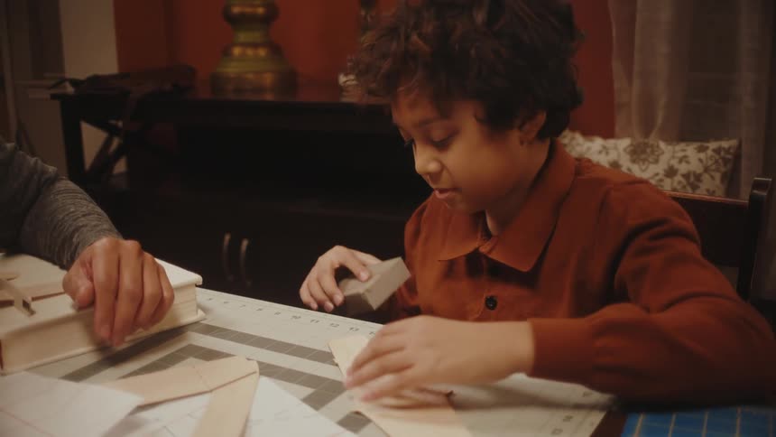 Father and son making toy paper planes in the living room