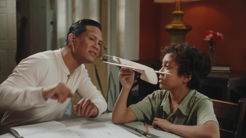 A father and son check out a model plane made out of cardboard