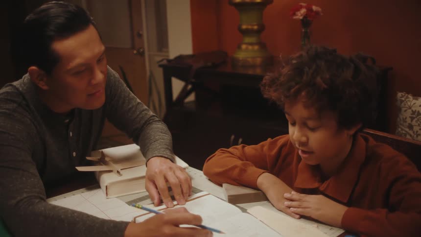 Father helping his son with homework in the living room