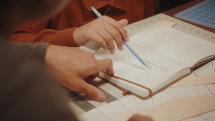 A man and a boy going through plans for a toy airplane drawn in a notebook