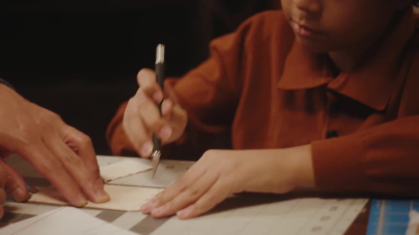 A child uses a pen knife to cut paper