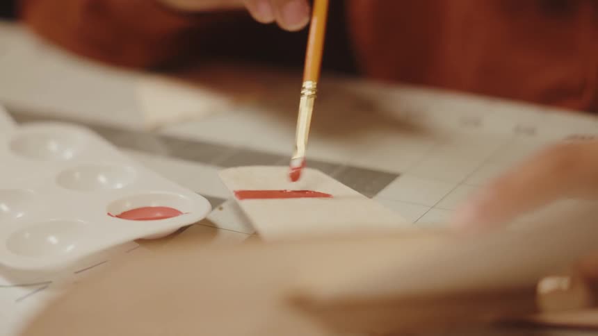 A boy painting the wing of a wooden toy airplane