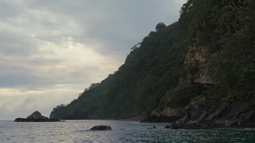 Calm sea next to the rocky coast on a cloudy morning