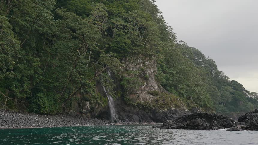 Landscape of the wooded seaside coast on a cloudy day and with a small waterfall