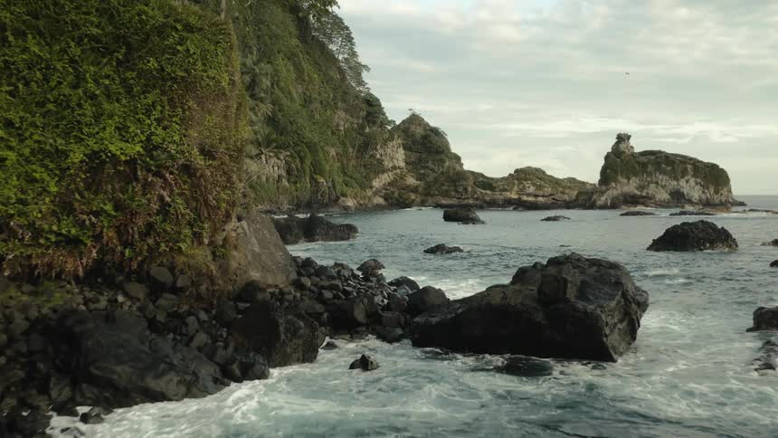 A sea coast with small waves breaking on the shore that is full of stone