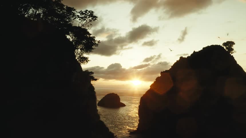 A sunset on a horizon at sea and in front there are small islets on a coast