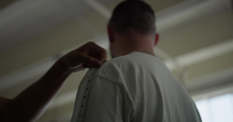 The tailor measures the mans shoulder