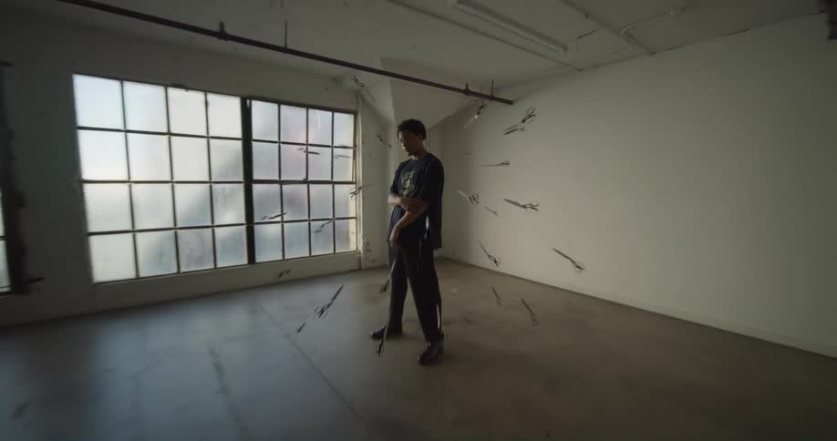 Floating scissors surround man standing in an empty room