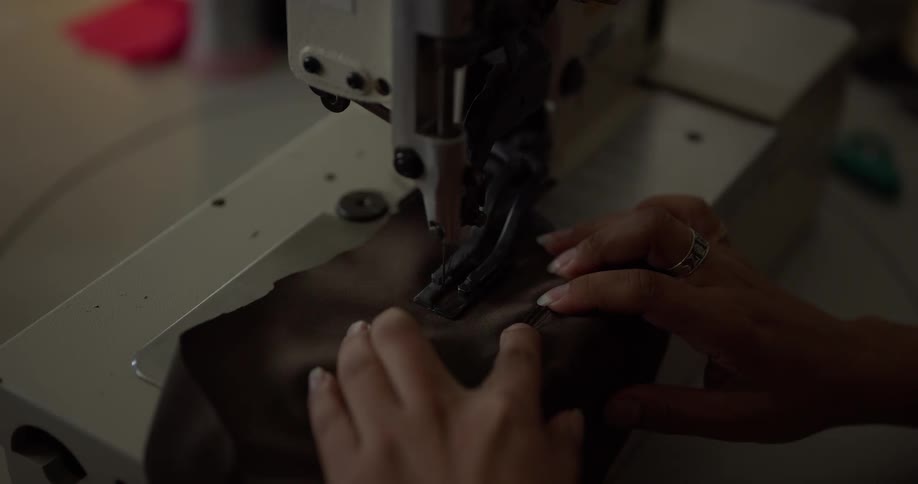 Woman operating a sewing machine to stitch brown fabric