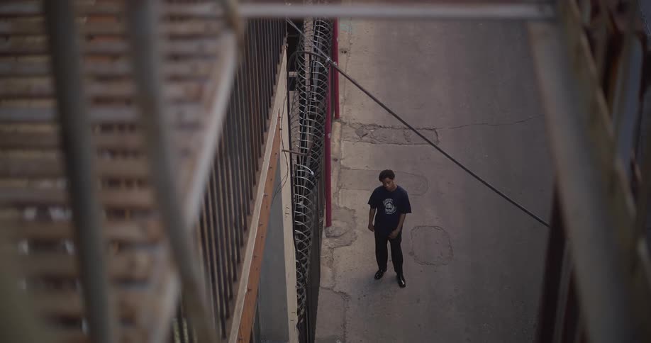 Man stands in courtyard of building near fence topped with razor wire