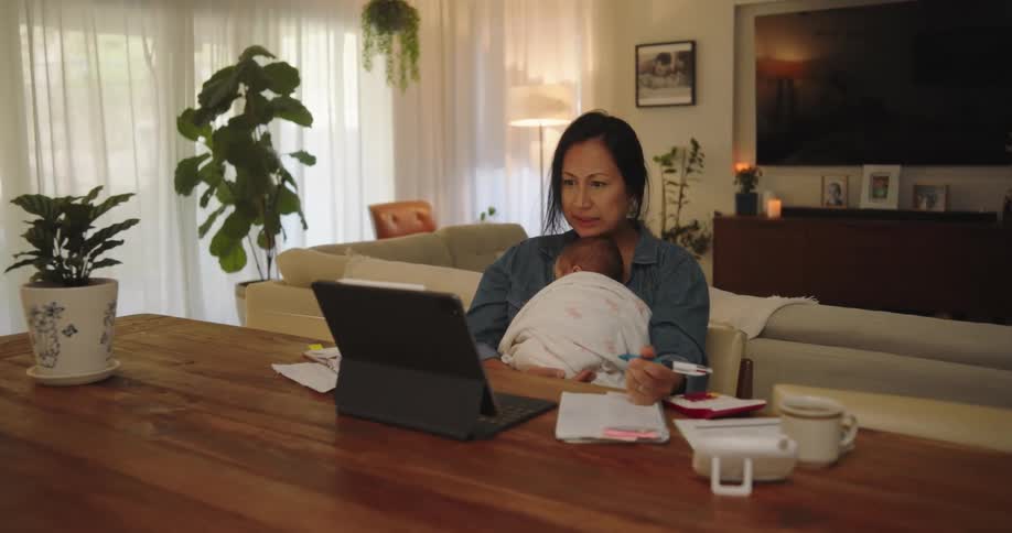 A woman with a baby on her lap writes in a notebook