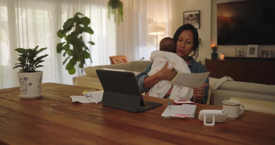A woman in a work meeting holds a baby on her lap