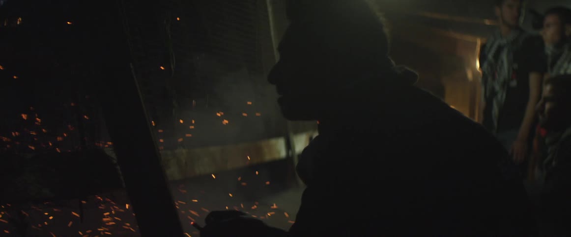 Man smokes a cigarette next to a flare in a dark room