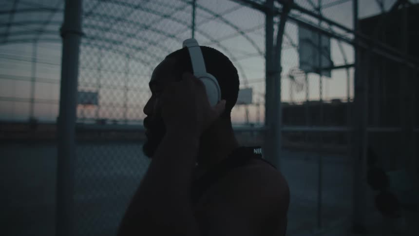 Bearded man wears a white headphone on a basketball court