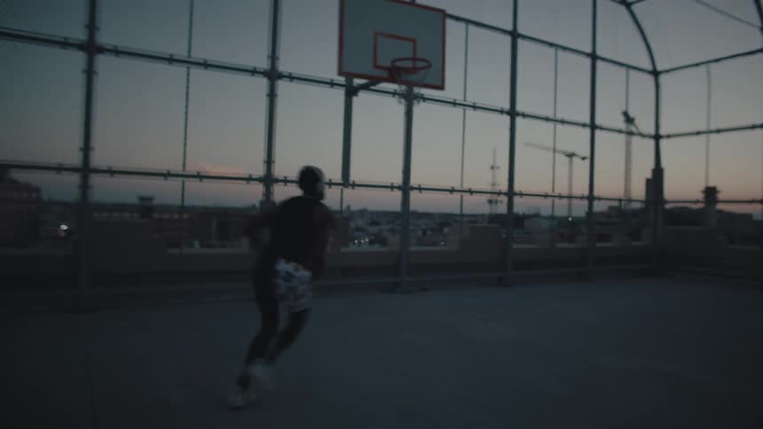 A guy plays basketball in an enclosed court