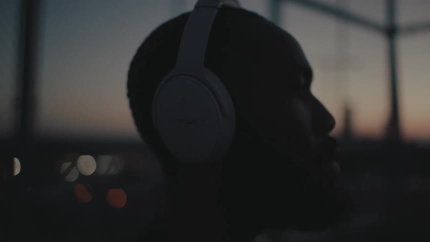 A man is listening to headphones at sunset