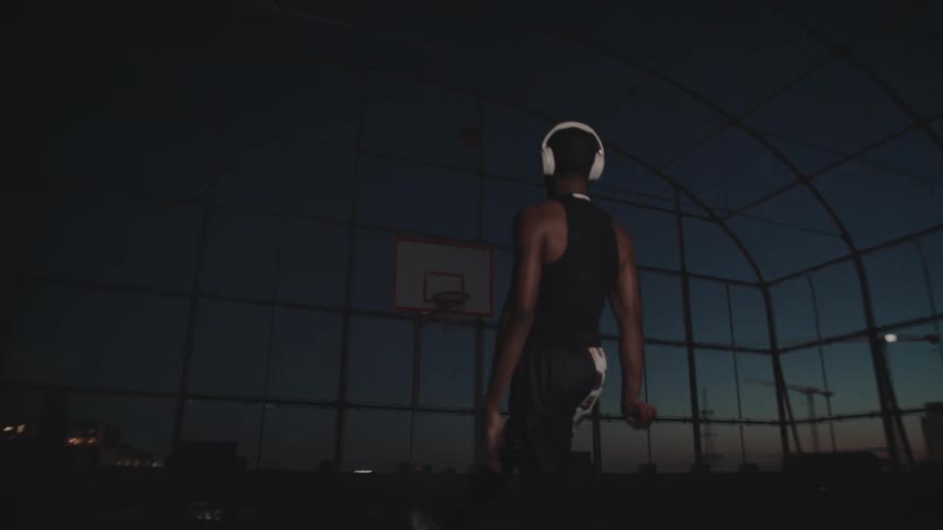 Man wearing white headphones shooting the ball through the hoop on a basketball court