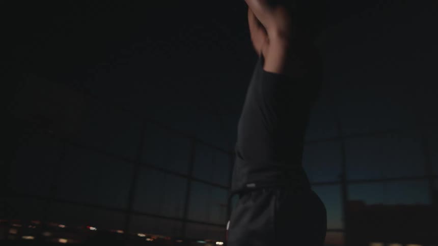 A man shoots the basketball at night