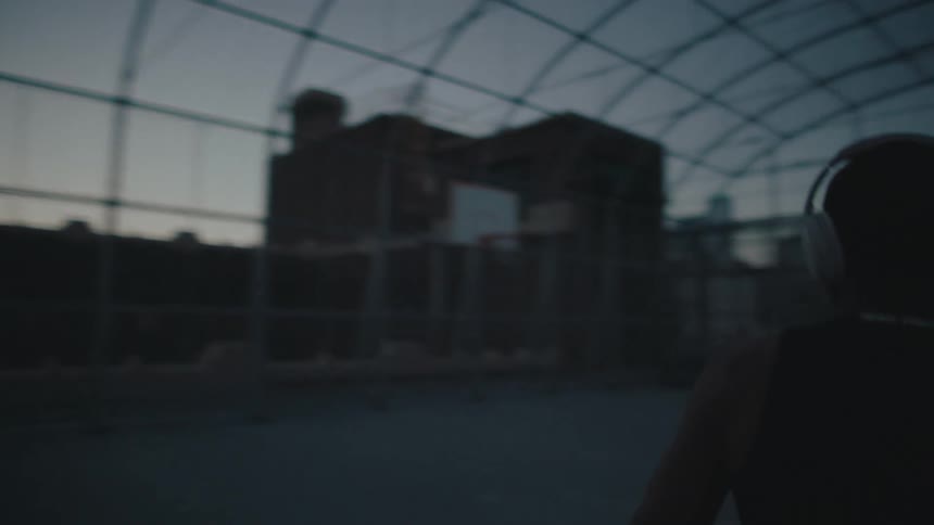 Man playing basketball on an open court in the late afternoon