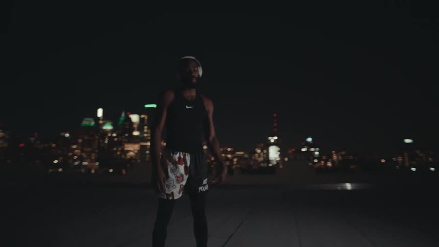 Man standing on a terrace with a basketball and using headphones