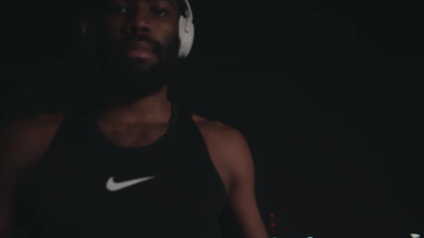 A man with a white headset is holding a basketball and moving back and forth