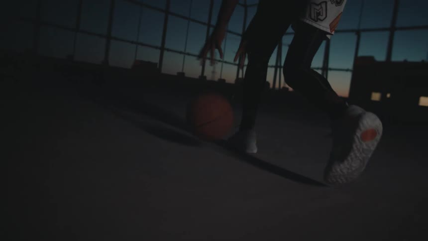 Hands and legs of a man training with a basketball on a terrace at night
