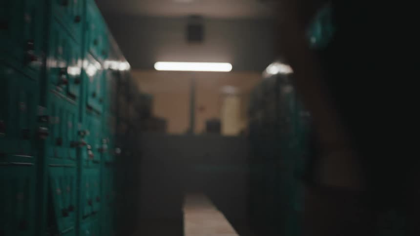 Woman stands from bench in dimly lit locker room
