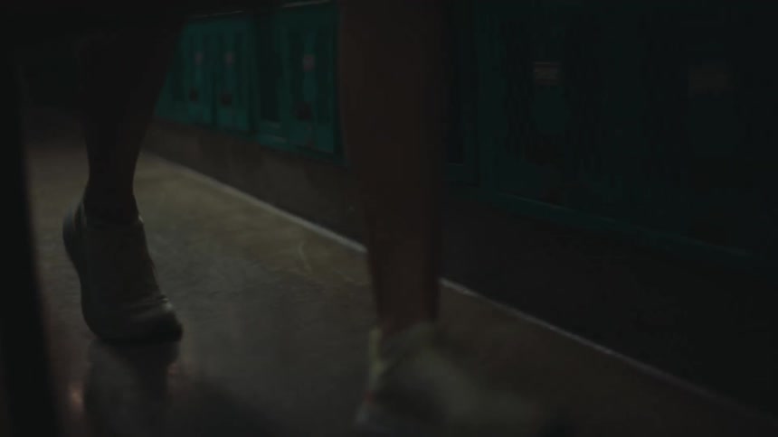 Person wearing sneakers walks past lockers in the locker room