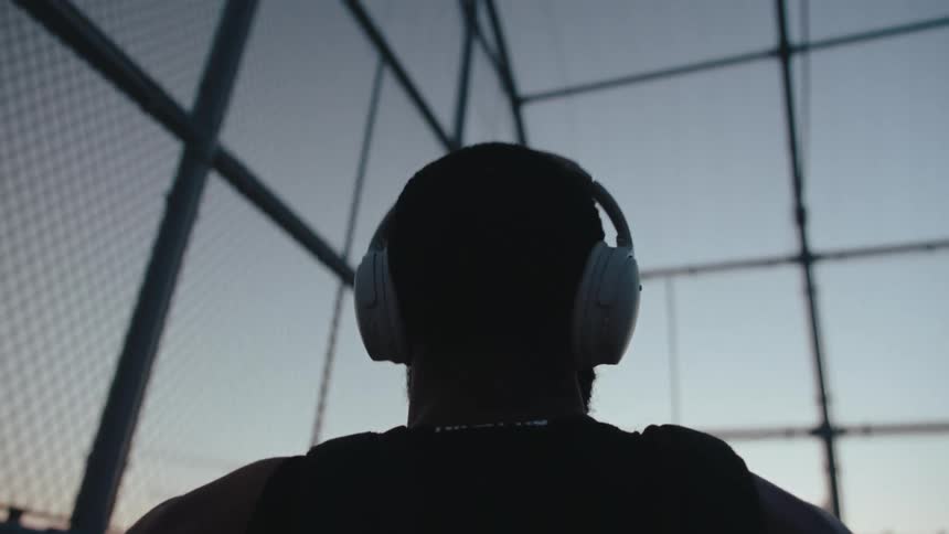 A man puts on headphones and bobs his head as he listens to music