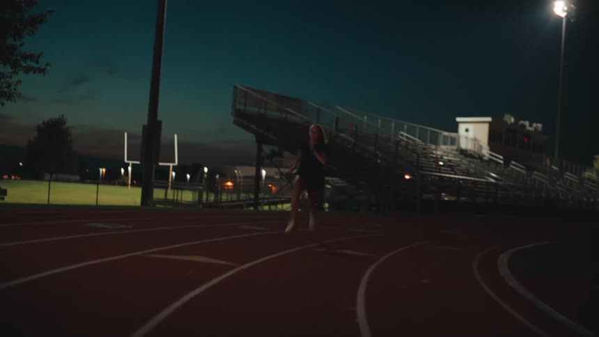A woman is running on a race track in a night